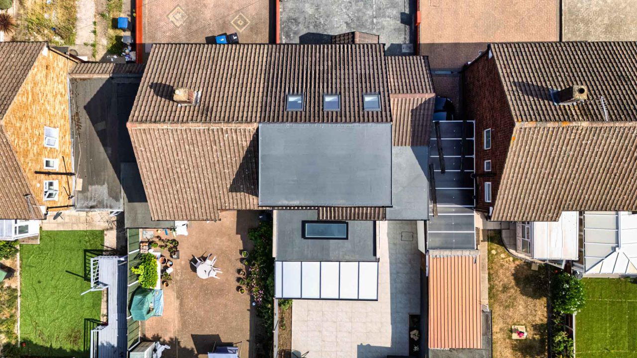 Aerial view of a house roof with roof windows and a flat-roofed extension